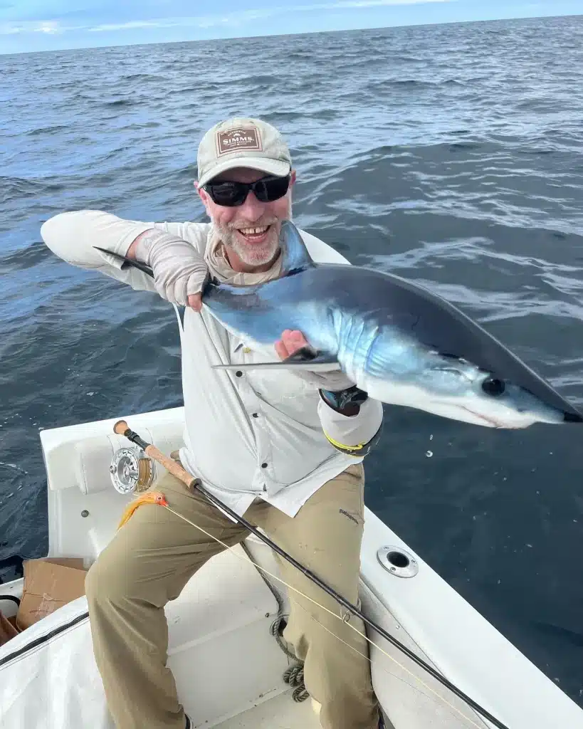 Successful fishing shark charter catch with trophy shark and excited angler posing in San Diego's crystal-clear offshore waters